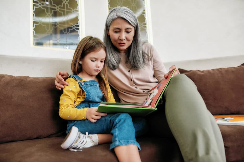 Grandma reading to granddaughter on couch