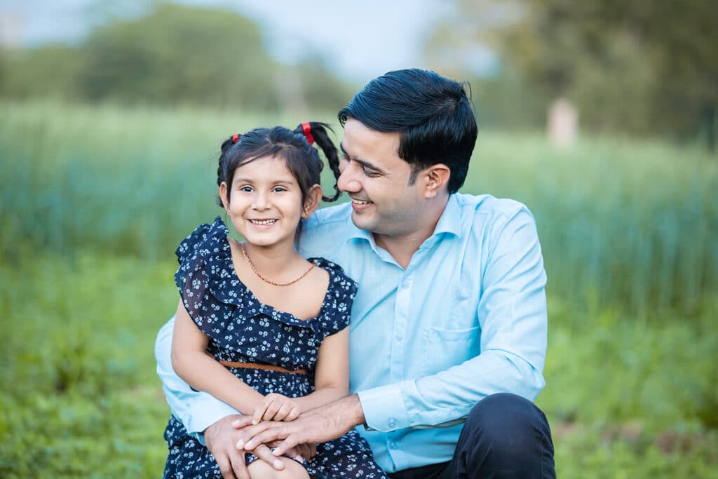 Dad with daughter in Grassy field smiling